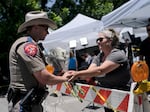 Sheena Rodriguez on Wednesday hands a state trooper a bouquet of flowers, honoring the victims killed in Tuesday's school shooting in Uvalde, Texas.
