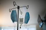 A patient receives an IV drip as face masks hang from an IV pole at a hospital in Portland, Ore., on Saturday, Aug. 8, 2020. Nurses and doctors in Oregon say they are finding little relief with coronavirus infections spreading at record levels, taxing the capacity of many hospitals.
