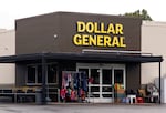 The exterior of a Dollar General store shows the budget retailer's signature brown siding and large yellow letters.
