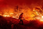 A firefighters in the midst of an inferno burning around them.