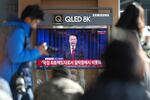 People watch a TV screen showing the live broadcast of South Korean President Yoon Suk Yeol's announcement at the Seoul Railway Station in Seoul, South Korea, on Saturday.