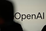 A person in silhouette stands in front of a screen showing OpenAI's logo.