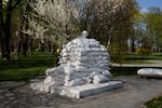 Sandbags surround a statue on a spring day in Kyiv.