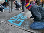 Toren McKnight of Central Point draws on the cement at the vigil for Aiden Ellison outside the Jackson County Justice Building