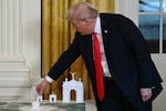 President Trump stands near models of his arch during an October 2025 event with White House ballroom donors. The administration's proposed design and location for the structure have changed little since then.