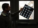 Braden Health's Kyle Kopec holds up a sample of diagnostic images left behind at an abandoned hospital they're taking over. They have to figure out what to do with old medical records stacked in boxes. (Blake Farmer for KHN)