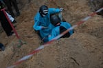 Ukrainian investigators exhume bodies from a mass grave site in Izium on Friday.