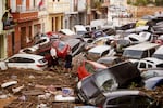 Residents look at cars piled up after being washed away by floods in Valencia, Spain, on Wednesday.