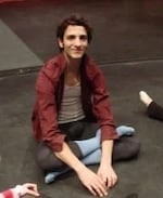 Paul Busch sits crossed legged on the floor wearing dance clothes.
