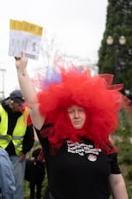 Alicia Arana, a volunteer with Multnomah East Indivisible, holds up ballots while wearing a red tulle wig at the rally.