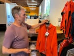 Showers Pass CEO Kyle Ranson shows one of his Elite cycling jackets at his store in Southeast Portland. He says he has to decide which items are worth bringing over to sell under the deeper tariffs.