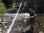 Biologist Pat Monk carries a bull trout to a cooler with water and anesthetic. They'll then collect DNA and tag each fish.