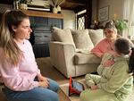 Emma, right, communicates with her sisters Ashley Lenover, left, and Kelsey Mercer using body language and a special tablet device.