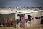 A displaced Palestinian woman hangs laundry to dry outside a tent at a makeshift camp on the Egyptian border, west of Rafah in the southern Gaza Strip on Jan. 14.