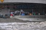 Sun., Aug. 20: Tents and belongings of unhoused people are seen near the rushing water of the Los Angeles River, near Griffith Park.