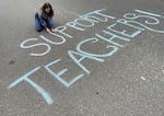 Capitol Hill Elementary School art teacher Allie Anderson writes a chalk message in front of the school on the first day of the Portland Public Schools strike in Portland, Ore., Nov. 1, 2023. The strike affects more than 80 campuses districtwide, with the exception of district charter schools. This is the first teacher strike in PPS history.