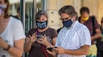 Voters check their phones while waiting to cast in-person ballots at a polling location in Austin, Texas, on Oct. 13, 2020. Many Americans wonder why they can't vote online, on their phones, but experts agree that it's not secure.