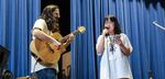 Linh Doan, right, sings her song for the Pass the Mic concert in Portland, Ore., Friday, Aug. 2, 2019. Sam Adams, left, of Portland band Sama Dams provides backing guitar.