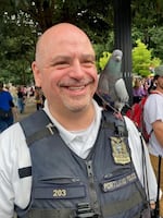 In this undated photo, provided by the City of Portland, Sergeant Daniel DiMatteo is pictured in his Dialogue Liaison Officer uniform, as a pigeon perches on his shoulder.