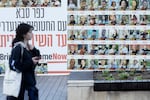 A woman passes by a wall covered with photos of hostages that were kidnaped to the Gaza Strip during Hamas deadly attack on January 6, 2025 in Kfar Saba, Israel.