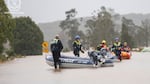 In this photo provided by the New South Wales Police, emergency workers wade through floodwaters as they prepare inflatable boats to effect rescues near Taree, Australia, Thursday, May 22, 2025. (NSW Police via AP)