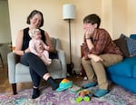 Two people sitting in a living room with a baby