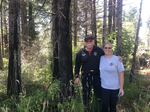 A couple stands next to a grove of charred trees on their property.