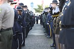 Law enforcement officers salute as Sgt. Jason Goodding’s casket is carried into the Seaside Convention Center.