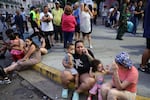 Evacuated people speak by phone while waiting at the Parque Central urban development complex.