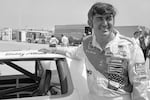 Bobby Allison stands beside his car and talks with the press after winning the pole position during qualifying for the 500 mile grand national stock car race at Pocono Raceway, Aug. 2, 1975, in Long Pond, Pa.