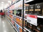 People shop at a Target store in Los Angeles where a sale sign is displayed for coffee pods on Feb. 13, 2023. Inflation has been easing since peaking last year, but it's still sturdier than many economists had expected.