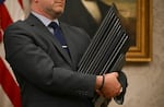 An aide holds a stack of bound executive orders.