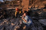 Saturday, Jan. 11: Ella Venne, front, holds a cup she found in the remains of her family's home destroyed by the Eaton Fire as she searches with Glendale Fire Department Capt. Chris Jernegan, left, and his wife, Alison, in Altadena.