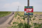 FILE - A tractor travels down Hunt Road in front of a "Let's Stop Lava Ridge" sign near the Minidoka National Historic Site, July 6, 2023, in Jerome, Idaho.