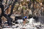 FILE - A woman digs through rubble of a home destroyed by a wildfire on Aug. 11, 2023, in Lāhainā, Hawaiʻi.