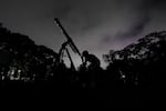 FILE - A girl looks at the moon through a telescope in Caracas, Venezuela, on Sunday, May 15, 2022.