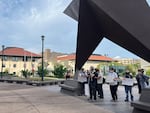 A small group of student protesters gathers under a statue of a large star outside Natal Con. A couple of signs read "Natalism is Nazism" and "No Nazis in Austin!"