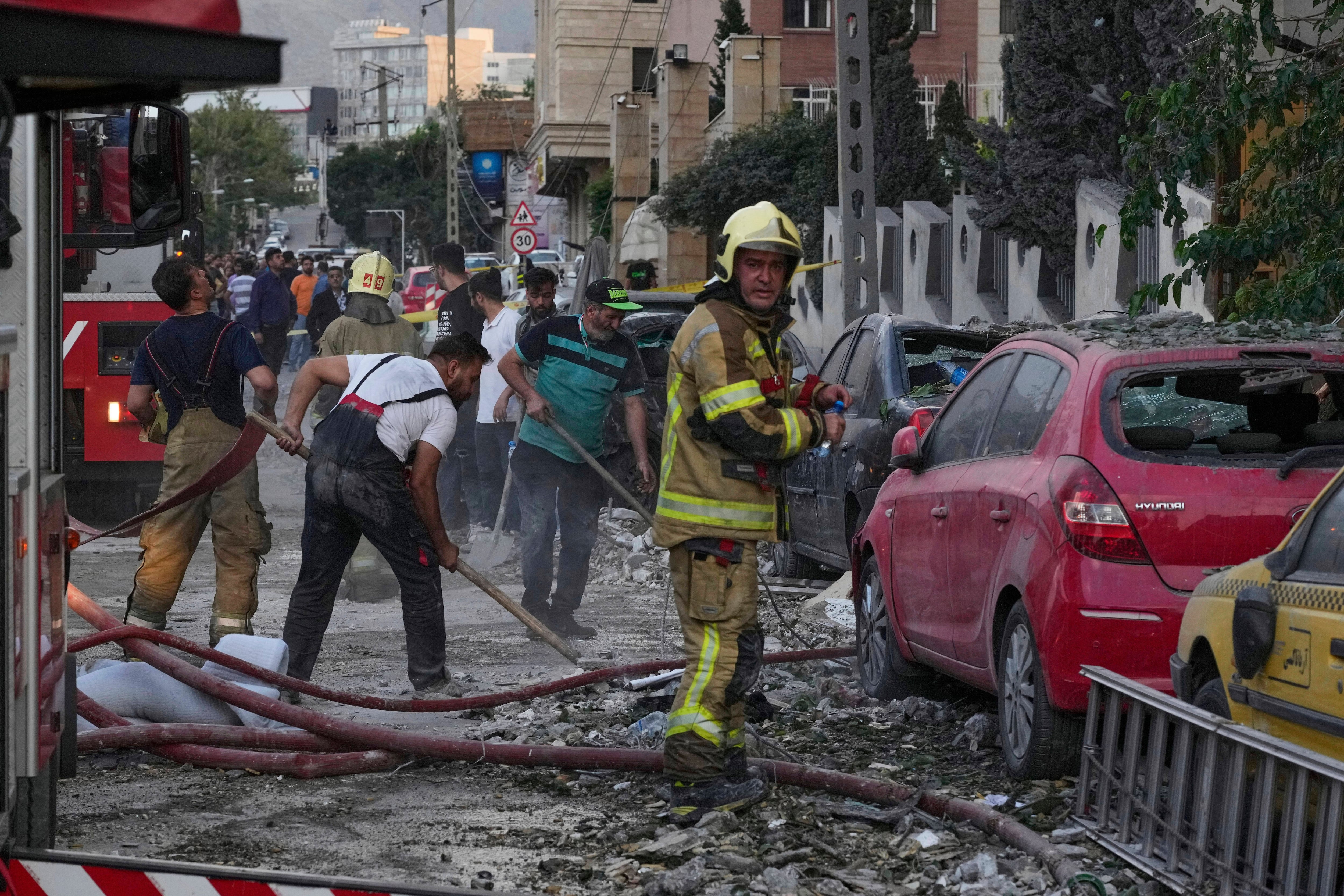 Firefighters and people clean up the scene of an explosion at a residence compound after Israeli attacks in Tehran on Friday.