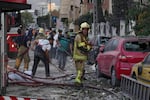 Firefighters and people clean up the scene of an explosion at a residence compound after Israeli attacks in Tehran on Friday.