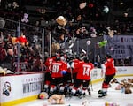 Portland Winterhawks players gather at the edge of the ice as teddy bears and other stuffed animals are tossed over the rink shield at the Teddy Bear Toss game, Dec. 10, 2022.