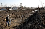 A construction worker takes measurements along a trench carved out for the repair of a levee in New Orleans in January 2006. Design flaws in the U.S. Army Corps of Engineers levee system contributed to widespread flooding and loss of life when Hurricane Katrina struck the year before.