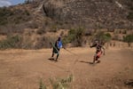 In the afternoon, when the work is done, the boys entertain themselves with an ancient game — throwing spears through a rolling hoop.
