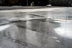 A vehicle drives as freezing rain falls on a sidewalk covered in ice on Jan. 17, 2024, in Tigard, Ore. Forecasters with the National Weather Service are warning people across central and north-central Oregon to expect freezing rain this week.