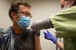 Eden Aldrich, right, medical director for the Deschutes County Sheriff's Office, administers the COVID-19 vaccine to Russ Hatch at the Deschutes County Public Health Department in Bend, Ore., Tuesday, Jan. 12, 2021.