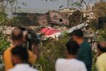 Onlookers watch wreckage from Thursday's Air India plane crash lying atop a building in Ahmedabad, India, Saturday, June 14, 2025.