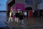 Owners of a deli business Karrar Hesham, far right, and sister Zahrha Hesham, far left, along with Hanadi Hesham, center, and Yousif Hesham, back, walk through the flood waters after checking on the state of their store, Wednesday, Dec. 10, 2025, in Auburn, Wash.