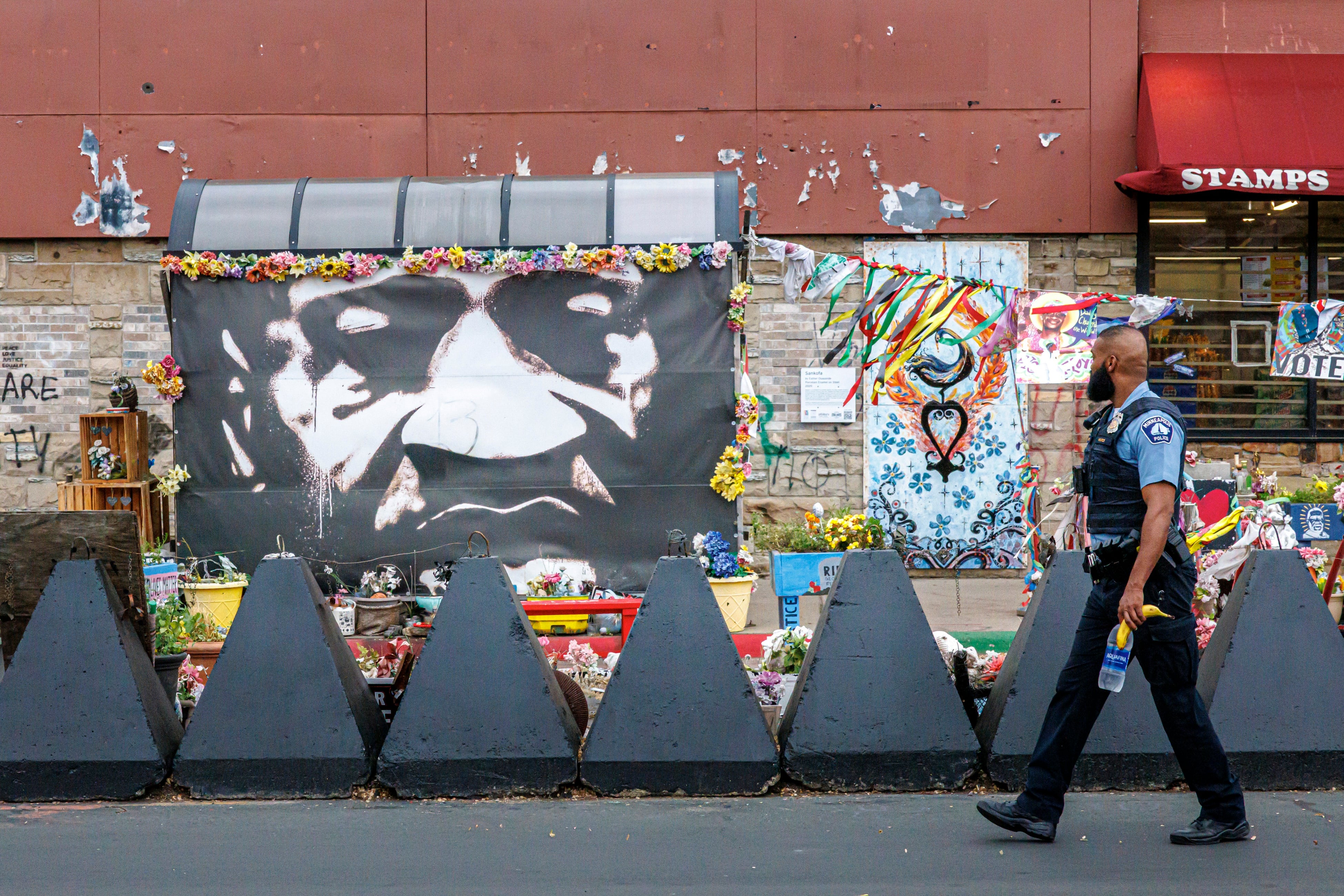 A Minneapolis police officer walks past a mural of George Floyd at the square.