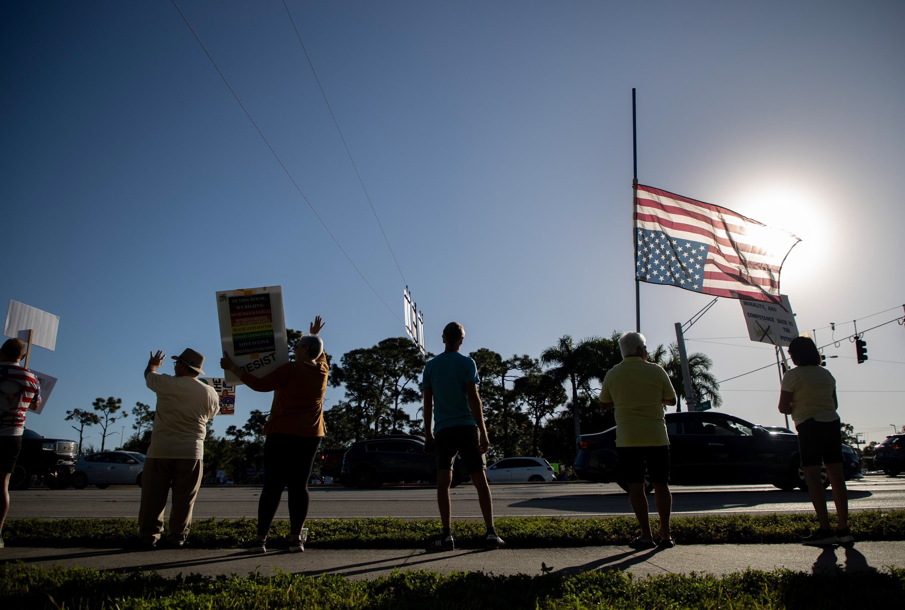 Demonstrators holding signs line the corner of Daniels Parkway and U.S. 41 in Fort Myers.