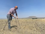 A farmer sifts the soil of one of his dry fields.