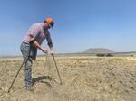 A farmer sifts the soil of one of his dry fields.